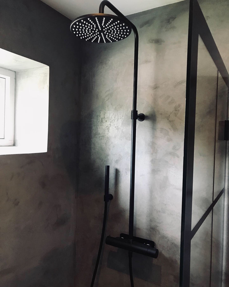 Badrum i mörkgrå microcement – dusch, fönster, vinkel