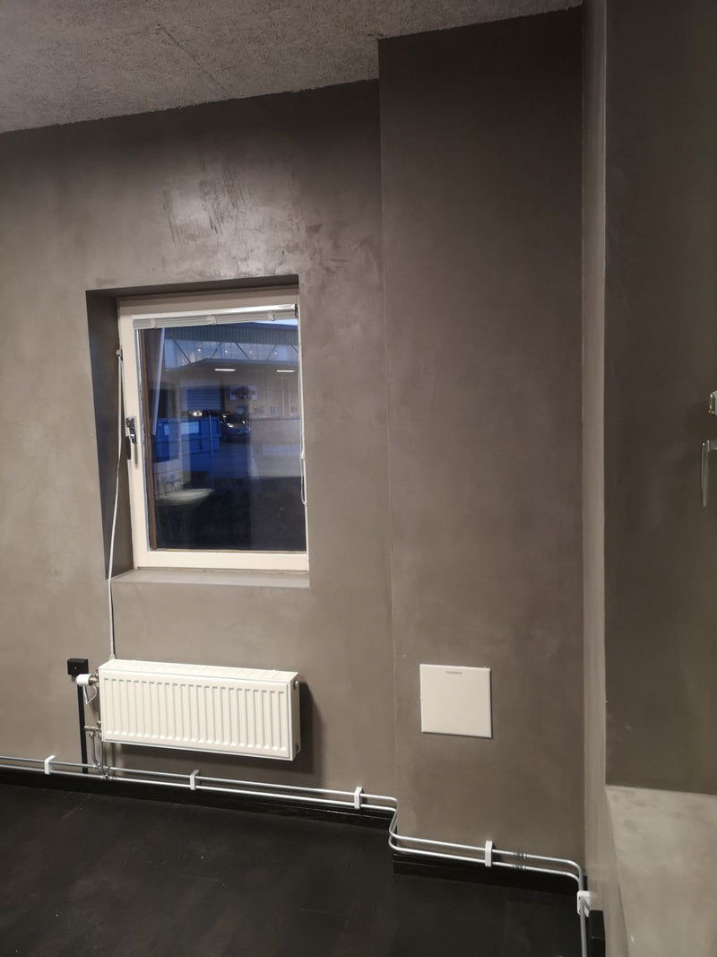 Vägg i mörkgrå microcement – fönster, element, hörn
