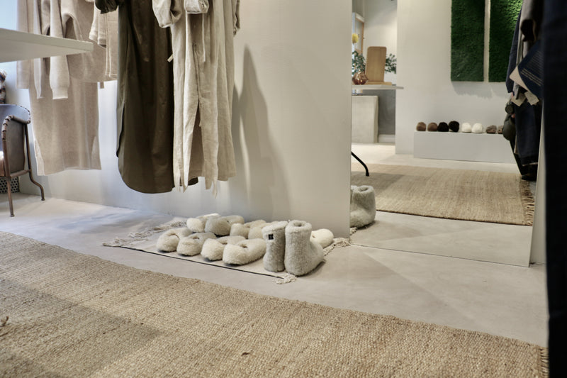 Interiör i gråbeige microcement – butiksmiljö, hängare, skor