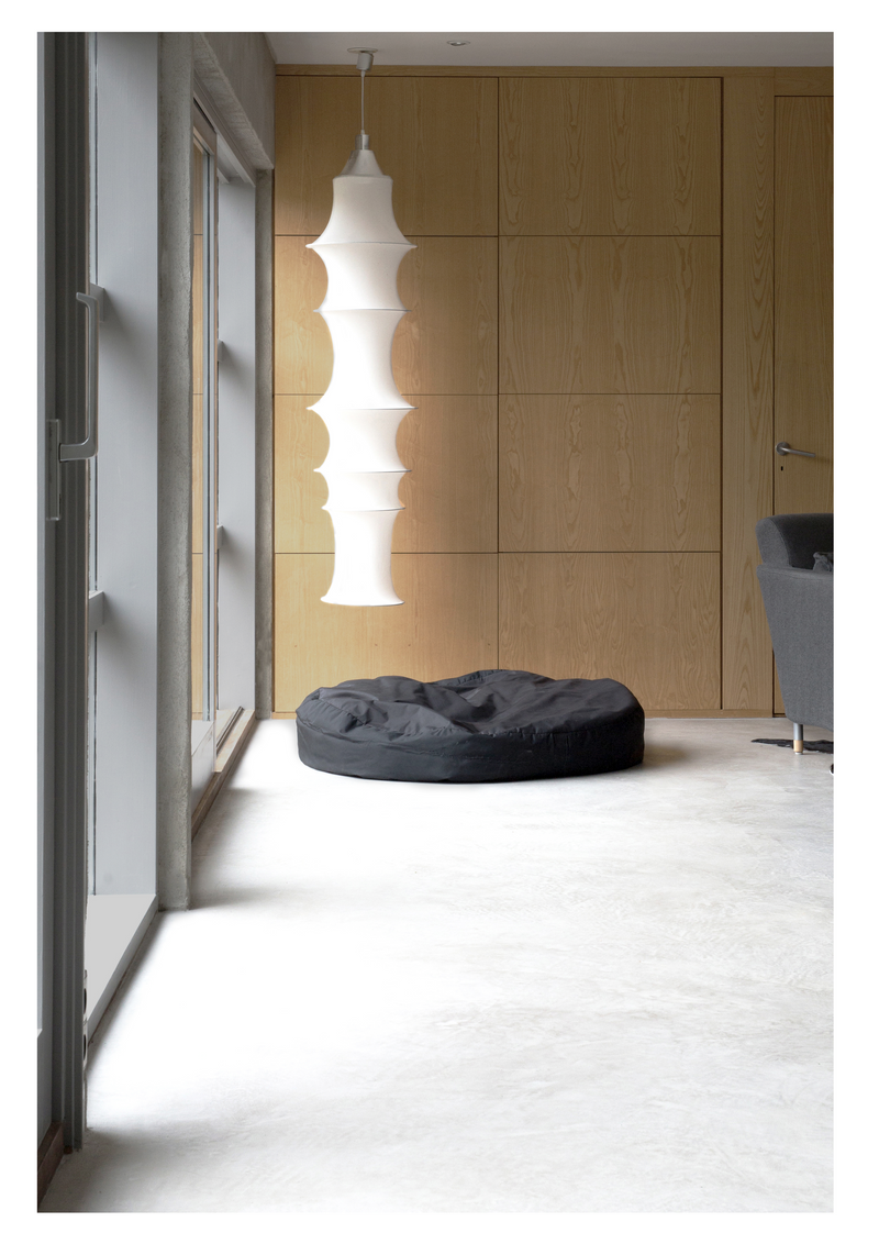 Interiör i betonggrå microcement – vardagsrum, lampa, sittsäck
