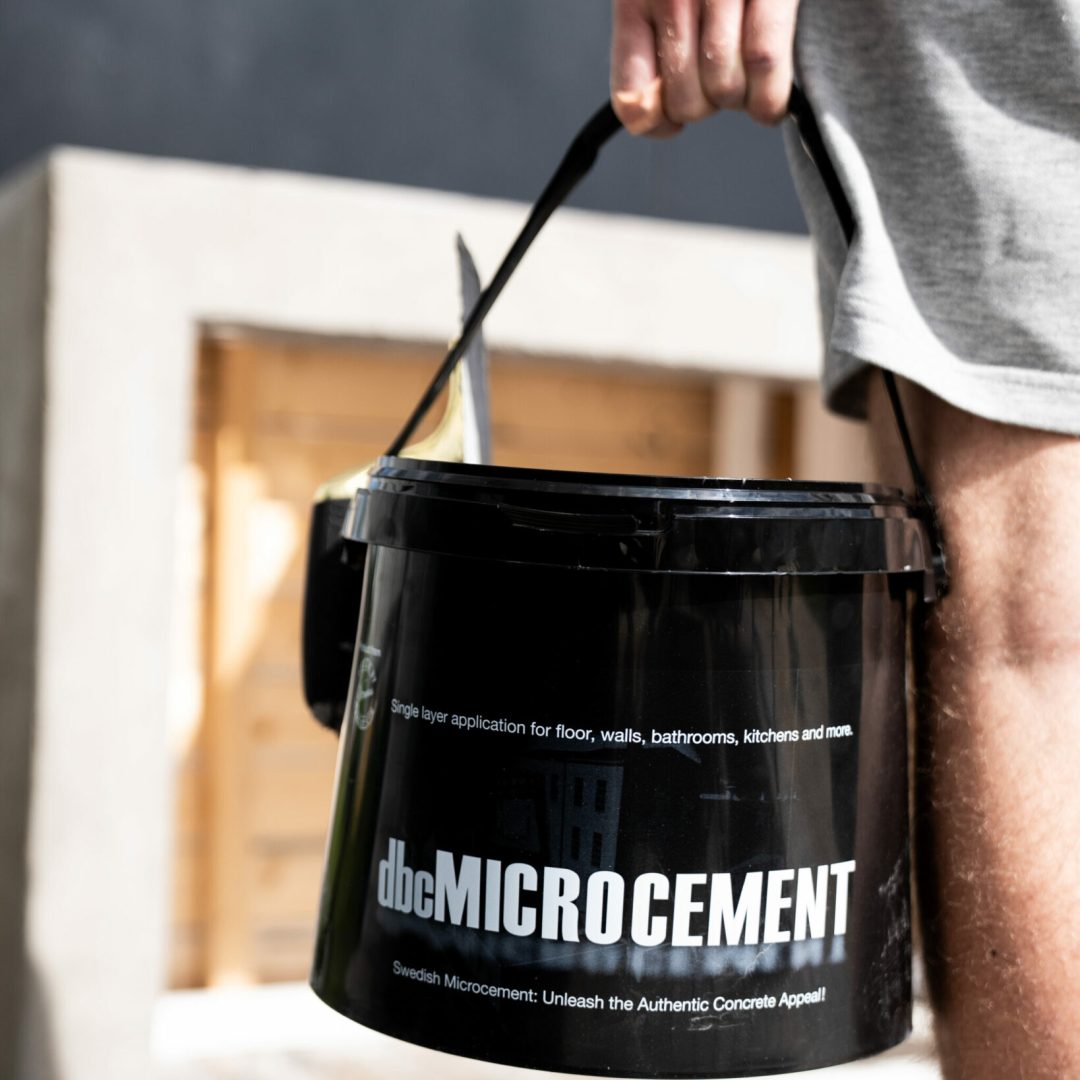 håller hink med microcement från designbycement